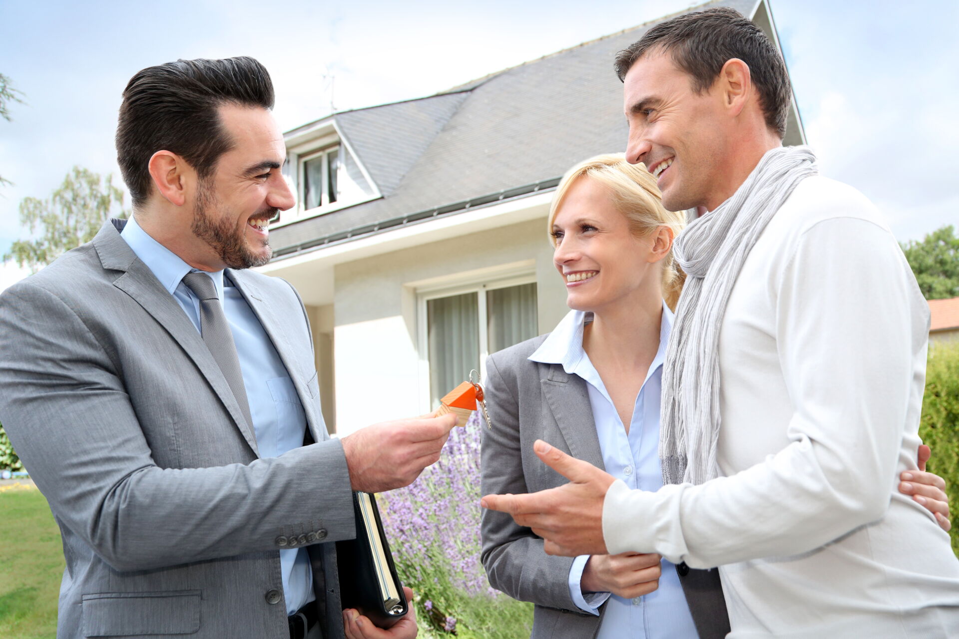 Pust & Partner GbR Makler übergibt Schlüssel an glückliches Paar vor ihrem neuen Haus in Berlin.