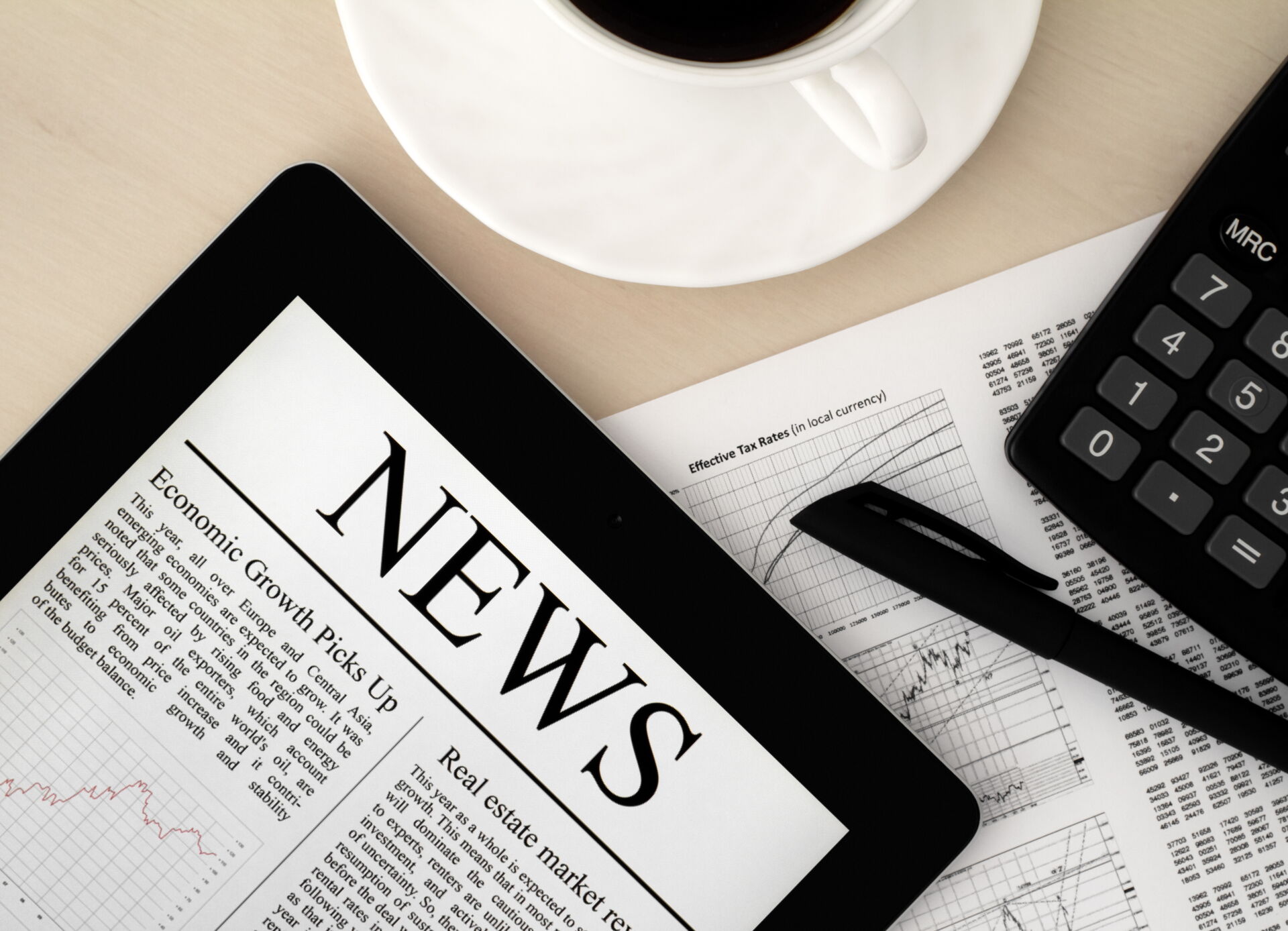Tablet mit "NEWS", Kaffeetasse und Rechner symbolisieren aktuelle Finanzinformationen von Pust & Partner GbR Berlin.